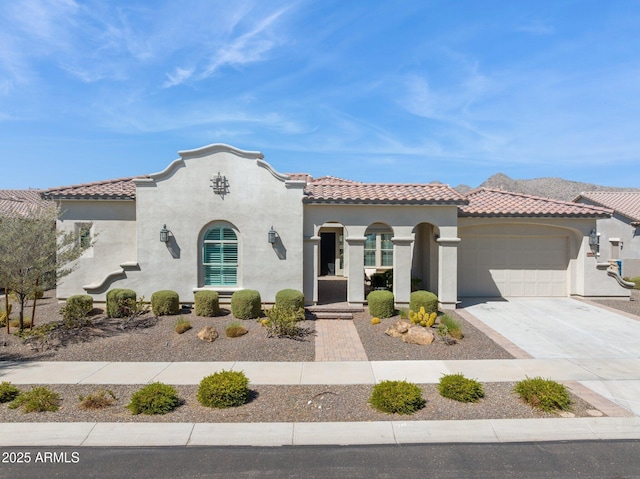 mediterranean / spanish home with a tiled roof, stucco siding, driveway, and a garage