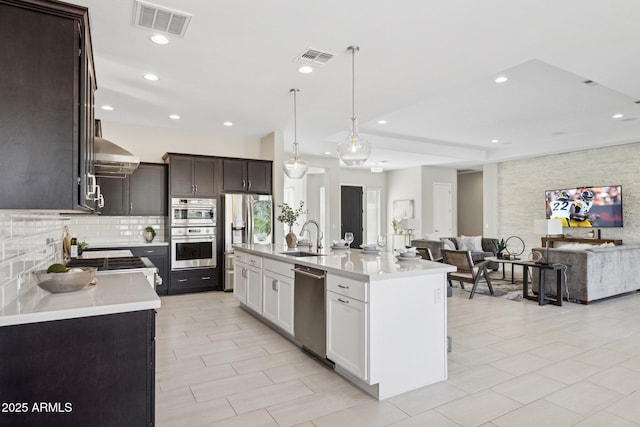 kitchen featuring light countertops, wall chimney range hood, visible vents, and appliances with stainless steel finishes