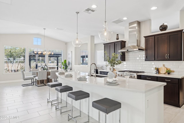 kitchen with tasteful backsplash, visible vents, wall chimney exhaust hood, and vaulted ceiling