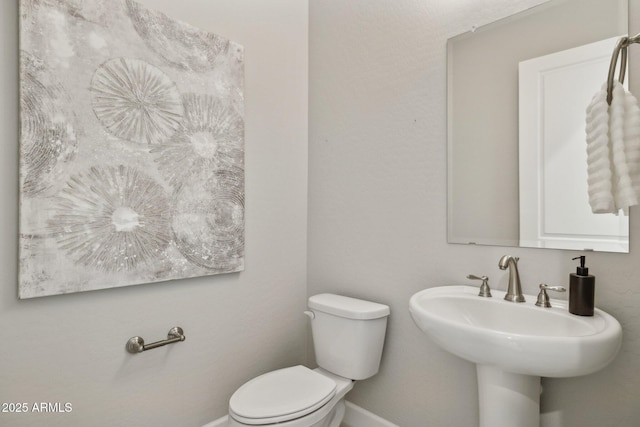 bathroom with a sink, baseboards, and toilet