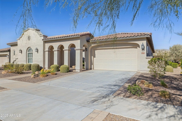 mediterranean / spanish-style house featuring stucco siding, driveway, an attached garage, and a tiled roof