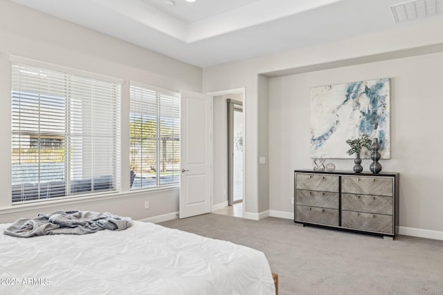 carpeted bedroom with a tray ceiling, visible vents, and baseboards