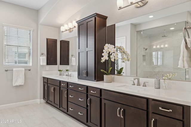 bathroom with a sink, an enclosed shower, baseboards, and double vanity