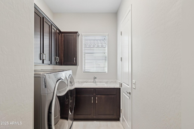 laundry area featuring cabinet space, independent washer and dryer, and a sink