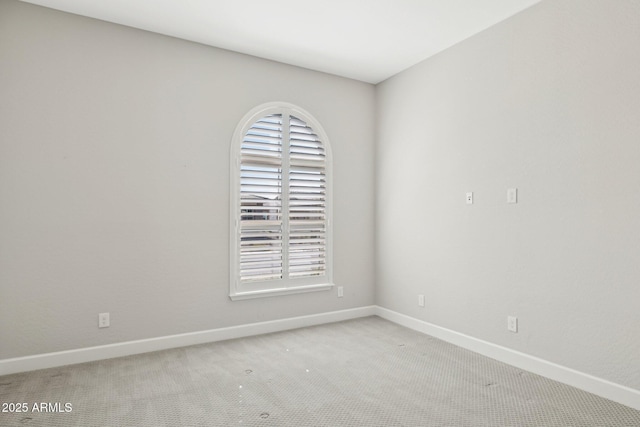 spare room featuring light colored carpet and baseboards