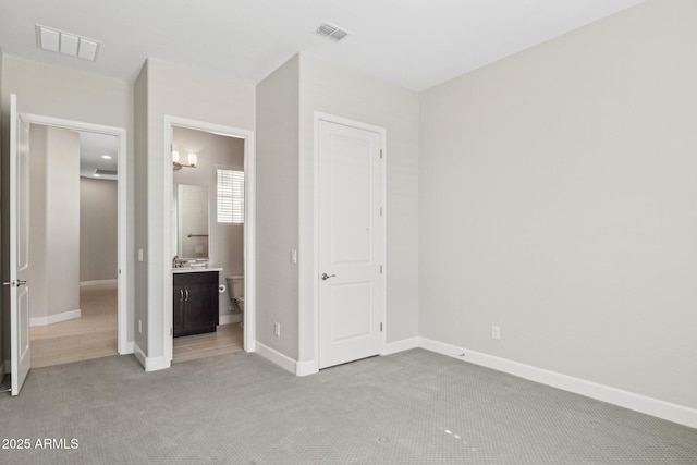 unfurnished bedroom featuring light carpet, visible vents, connected bathroom, and baseboards