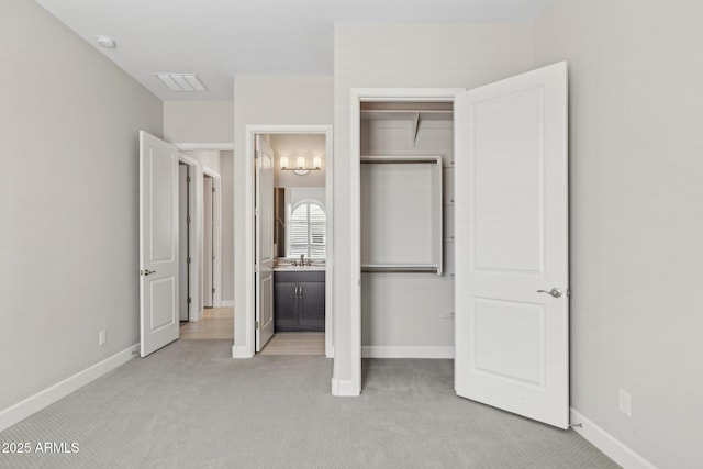 unfurnished bedroom featuring baseboards, light colored carpet, visible vents, and a sink