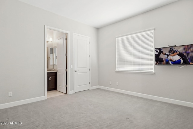 unfurnished bedroom featuring light colored carpet, baseboards, and connected bathroom