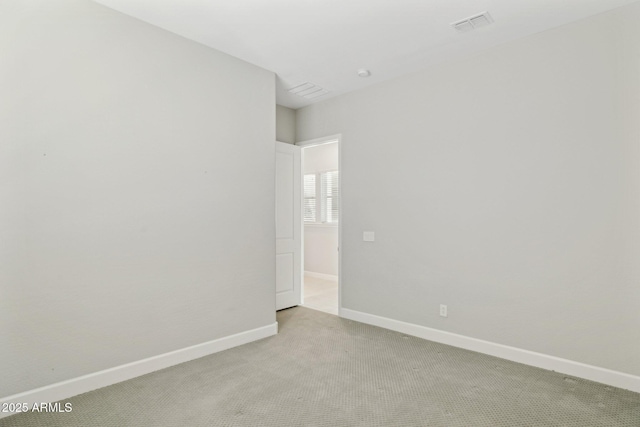 spare room featuring light carpet, visible vents, and baseboards