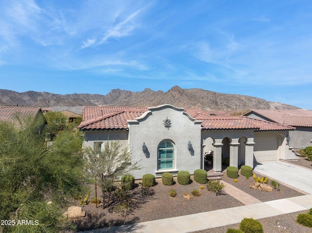 mediterranean / spanish-style house with stucco siding, a mountain view, concrete driveway, an attached garage, and a tiled roof