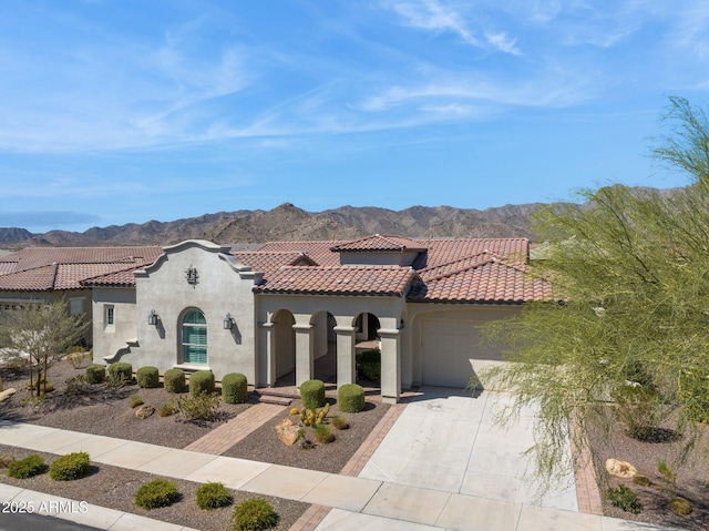 mediterranean / spanish home featuring stucco siding, a mountain view, a tile roof, and a garage