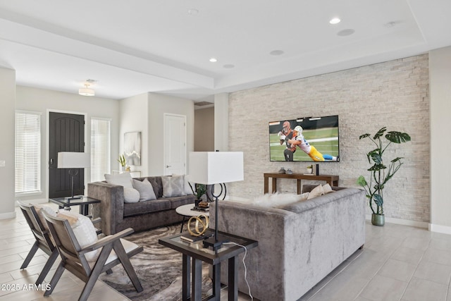 living area with a tray ceiling, recessed lighting, and baseboards