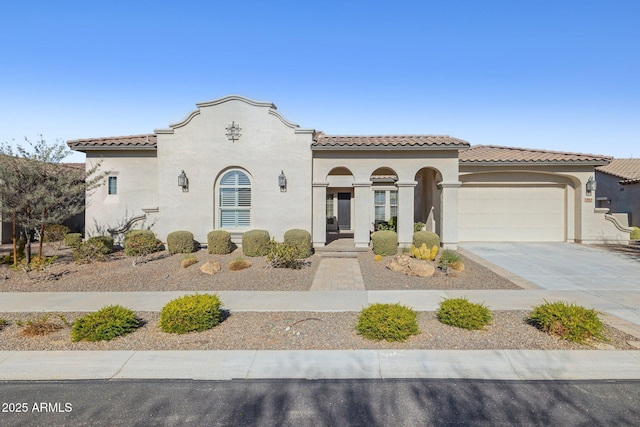 mediterranean / spanish-style home with a tile roof, concrete driveway, an attached garage, and stucco siding