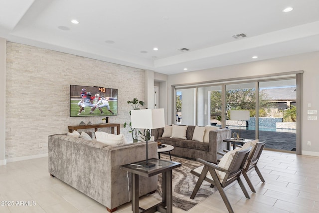 living room featuring a tray ceiling, recessed lighting, visible vents, and baseboards