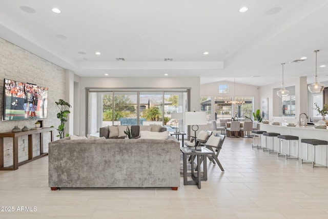 living area featuring an inviting chandelier, a raised ceiling, recessed lighting, and visible vents