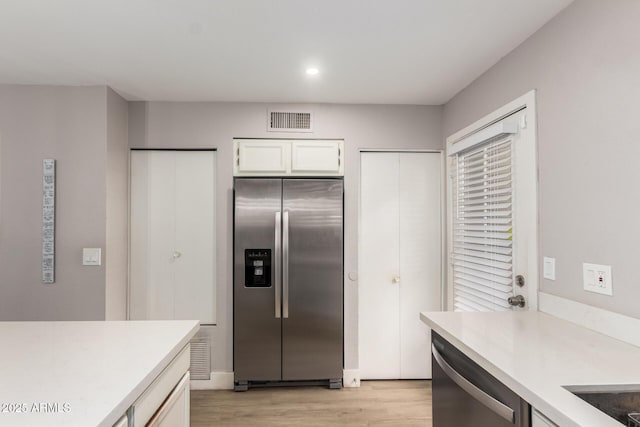 kitchen featuring white cabinetry, light hardwood / wood-style floors, and appliances with stainless steel finishes