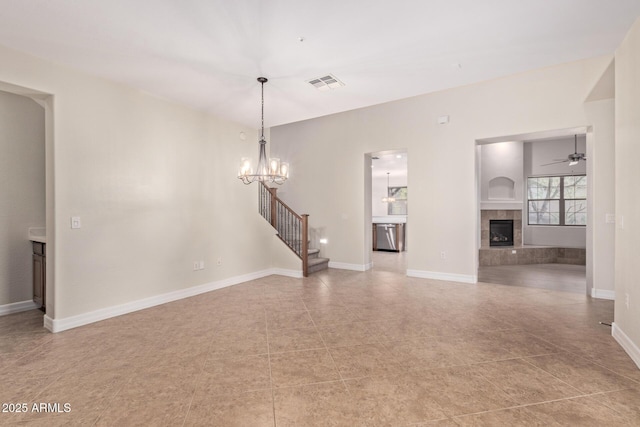 unfurnished living room with a tile fireplace, visible vents, stairway, and baseboards