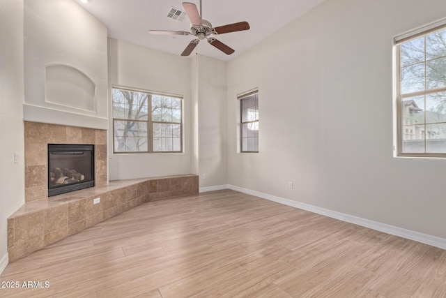 unfurnished living room with a healthy amount of sunlight, a fireplace, baseboards, and wood finished floors