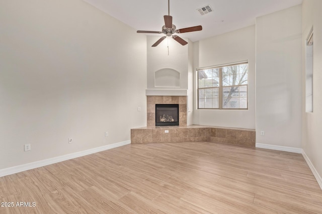 unfurnished living room with ceiling fan, wood finished floors, visible vents, and baseboards