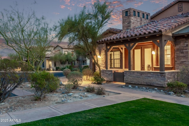 doorway to property with stone siding, a tile roof, a chimney, and stucco siding