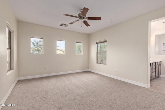 empty room with baseboards, plenty of natural light, visible vents, and light colored carpet