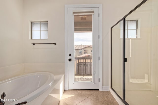 full bathroom featuring a garden tub, a shower stall, and tile patterned floors