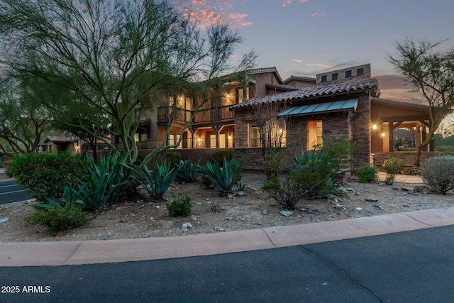 view of front facade featuring stone siding, a tiled roof, and stucco siding