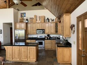 kitchen with lofted ceiling, stainless steel appliances, wood ceiling, dark countertops, and a ceiling fan