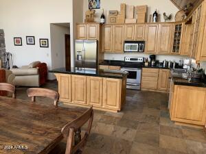 kitchen with a kitchen island, dark countertops, appliances with stainless steel finishes, and glass insert cabinets