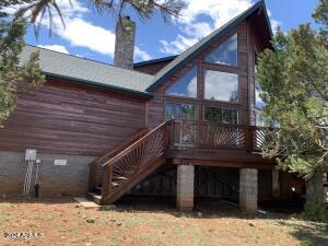 back of house with a chimney, a deck, and stairway