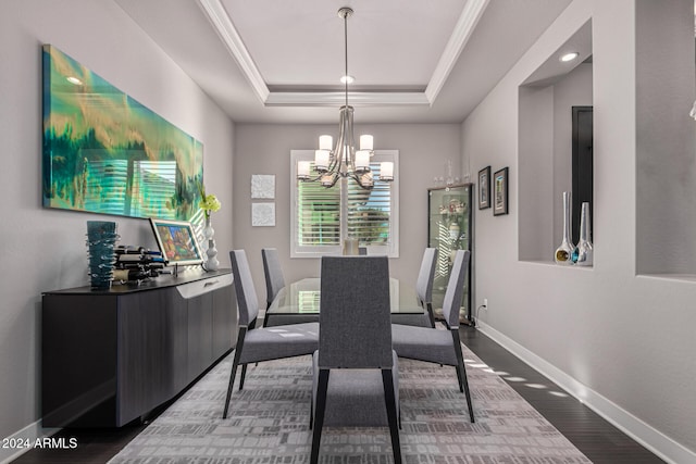 dining area with a raised ceiling, a chandelier, wood-type flooring, and ornamental molding