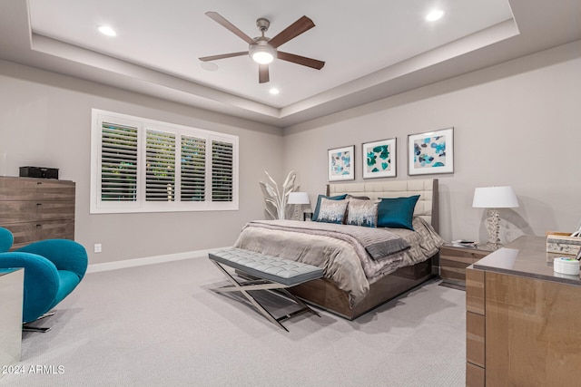 carpeted bedroom with ceiling fan and a raised ceiling