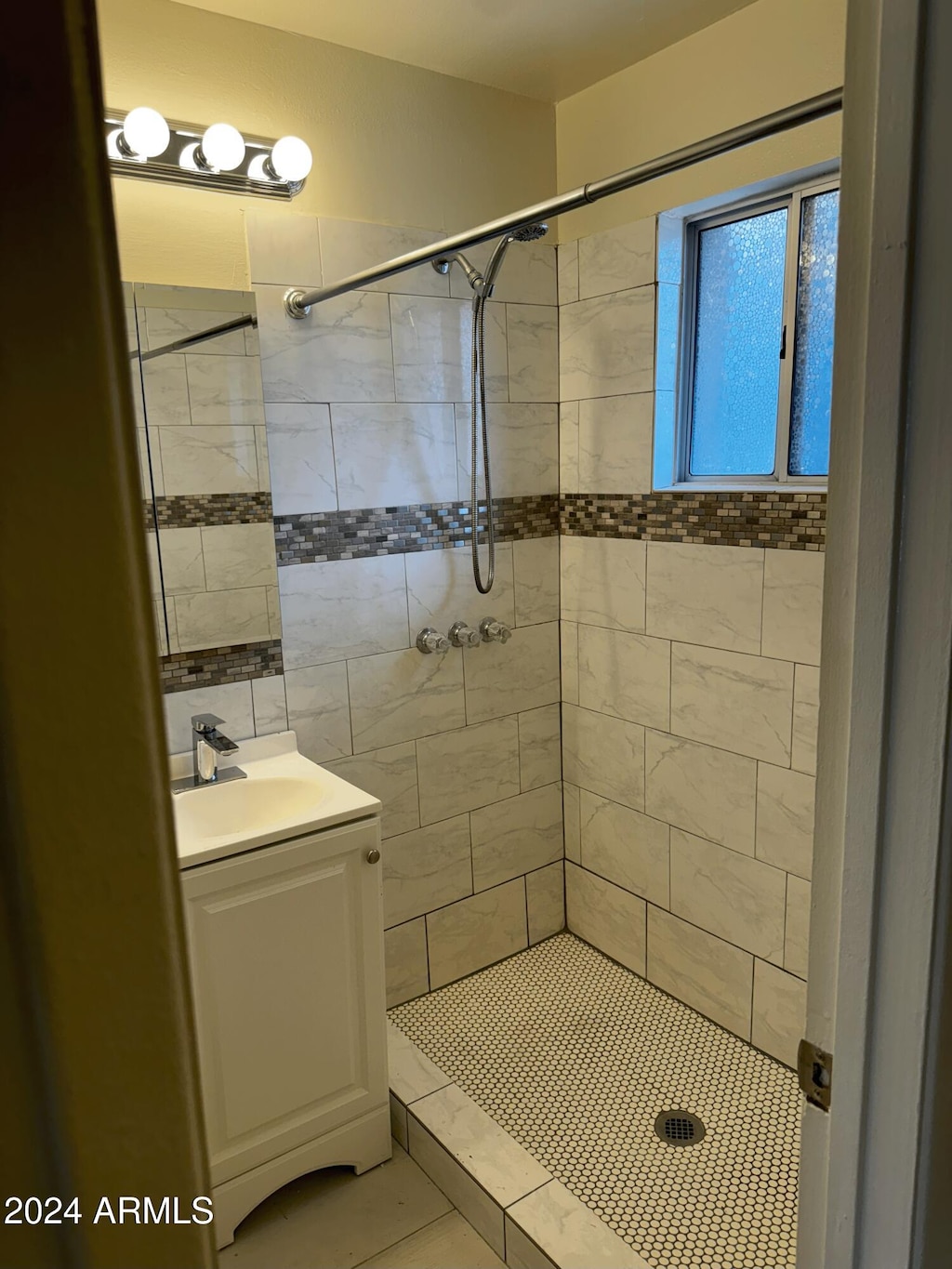 bathroom featuring vanity, a tile shower, and tile patterned floors