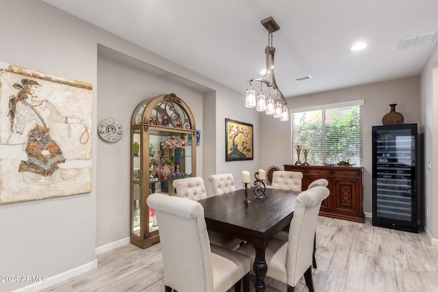 dining space with wine cooler and light hardwood / wood-style floors