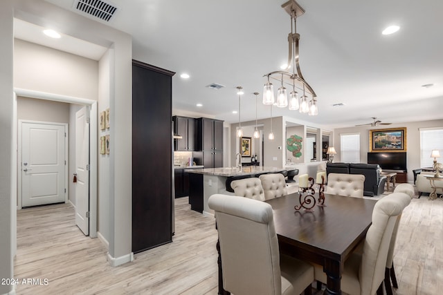 dining space with ceiling fan, light hardwood / wood-style flooring, and sink