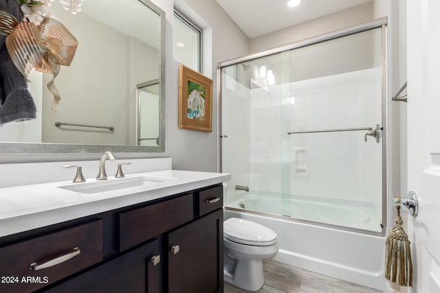 full bathroom featuring enclosed tub / shower combo, hardwood / wood-style flooring, vanity, and toilet