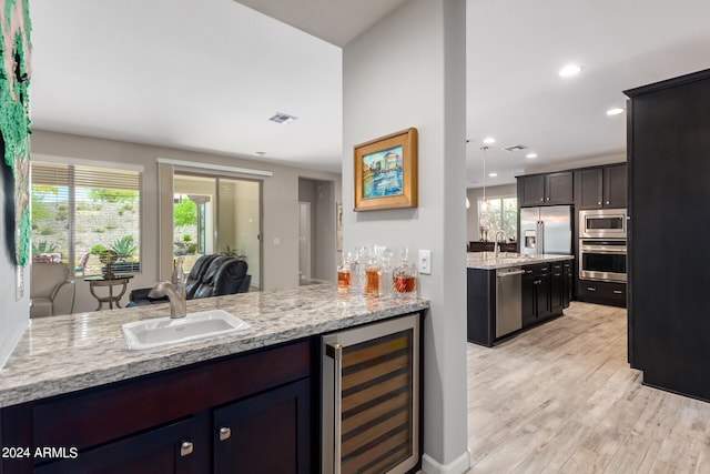 kitchen featuring stainless steel appliances, light hardwood / wood-style floors, beverage cooler, and a healthy amount of sunlight