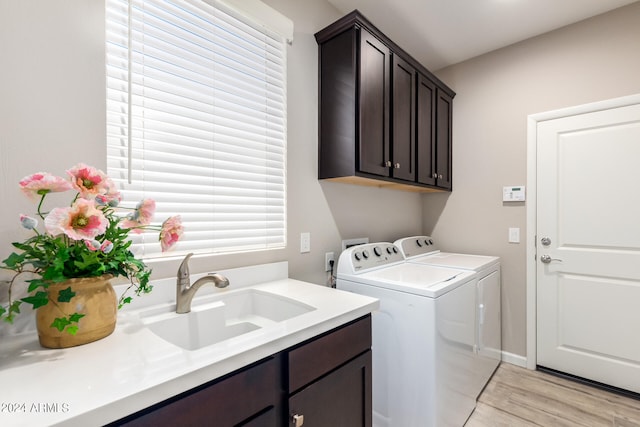 clothes washing area with light hardwood / wood-style floors, cabinets, washer hookup, sink, and washing machine and dryer