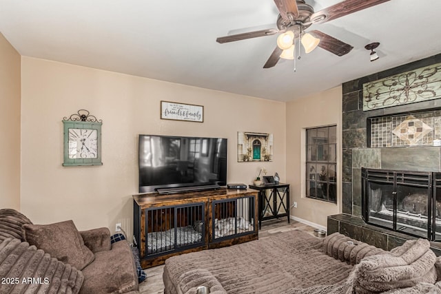 6133 E Saddleback St, Mesa, AZ 85215 - living room with wood finished floors, a tiled fireplace, ceiling fan, and baseboards