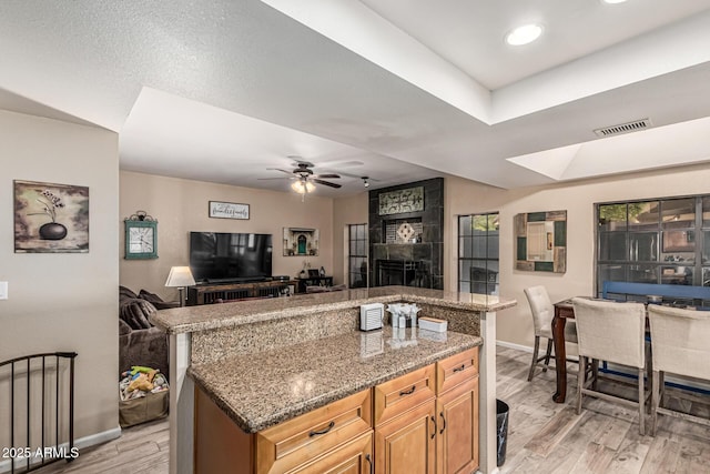 6133 E Saddleback St, Mesa, AZ 85215 - kitchen with open floor plan, baseboards, light wood-style floors, a large fireplace, and light stone counters