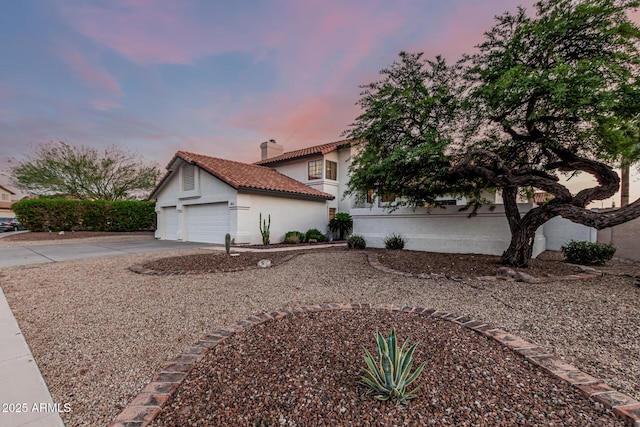 6133 E Saddleback St, Mesa, AZ 85215 - property exterior at dusk with stucco siding, a chimney, a tile roof, concrete driveway, and an attached garage