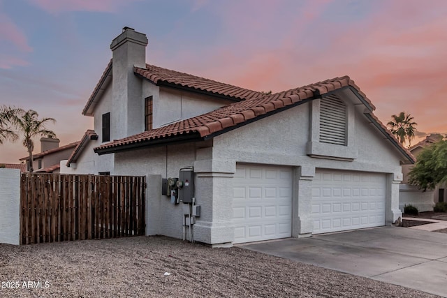 6133 E Saddleback St, Mesa, AZ 85215 - property exterior at dusk featuring driveway, a tiled roof, a garage, a chimney, and stucco siding