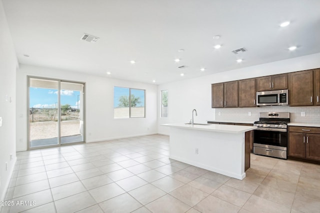 kitchen featuring appliances with stainless steel finishes, a sink, light countertops, backsplash, and visible vents