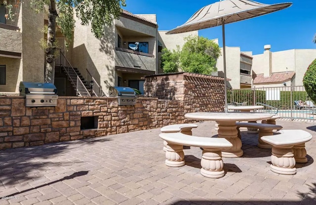 view of patio / terrace with a balcony, area for grilling, an outdoor kitchen, and a fenced in pool