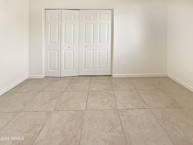 unfurnished bedroom featuring light tile patterned floors and a closet