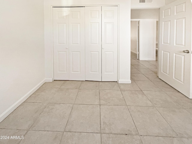 unfurnished bedroom with light tile patterned floors and a closet