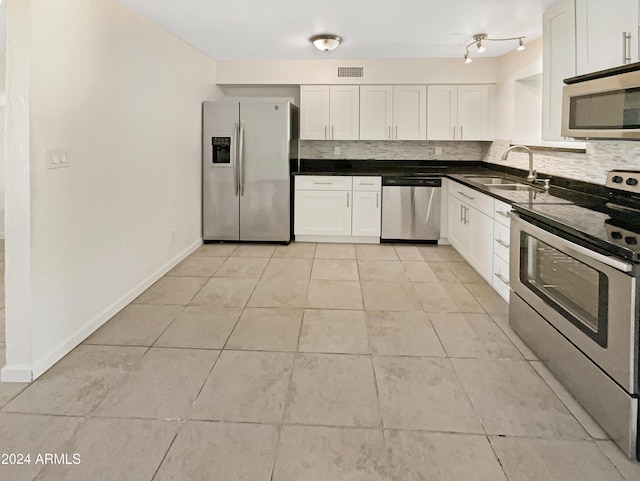 kitchen with backsplash, stainless steel appliances, sink, light tile patterned floors, and white cabinetry