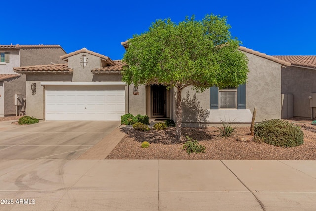 view of front facade with a garage, driveway, a tiled roof, and stucco siding