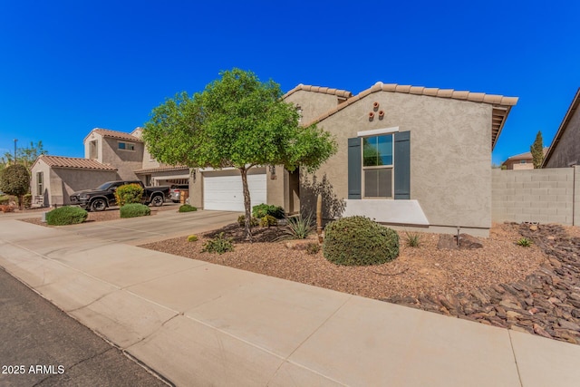 mediterranean / spanish home with a tile roof, stucco siding, concrete driveway, an attached garage, and fence