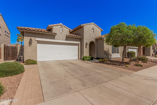 mediterranean / spanish-style home with driveway, an attached garage, a tiled roof, and stucco siding